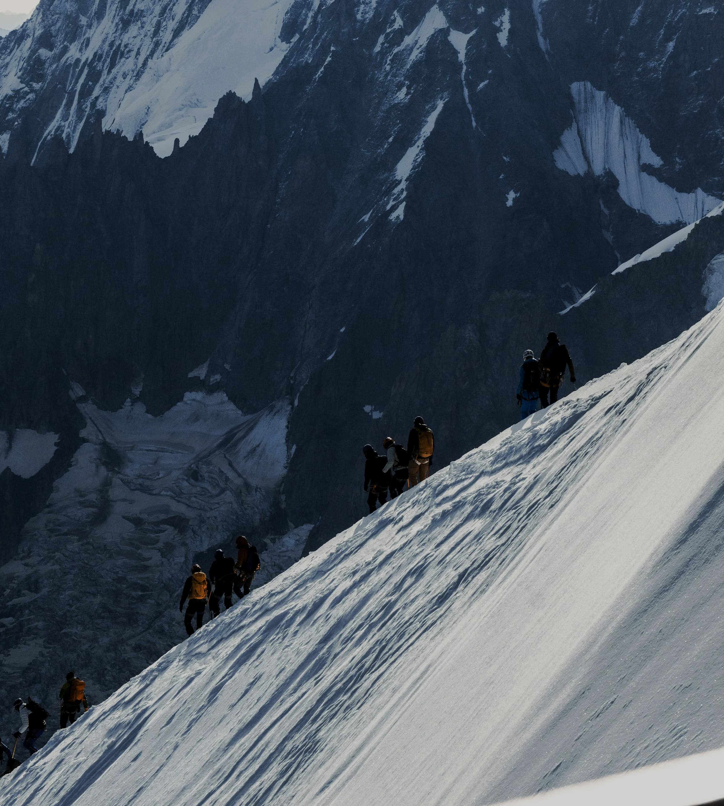 A rope team of mountaineers climbs a snowy Alpine slope